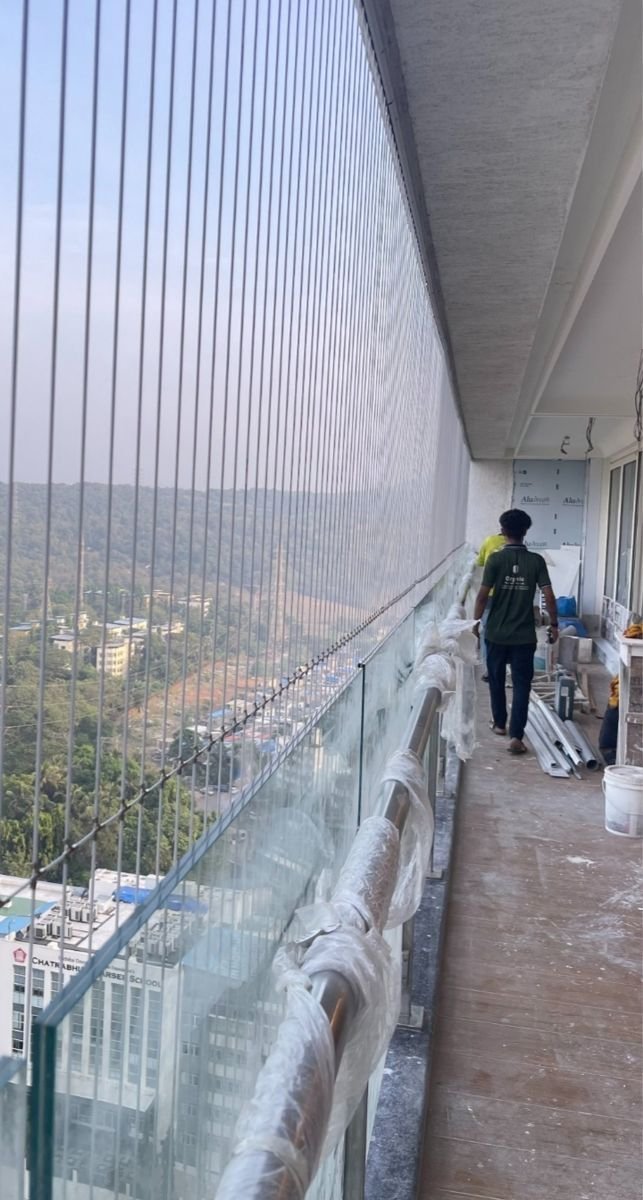 Invisible grill installation in progress along a long high-rise balcony